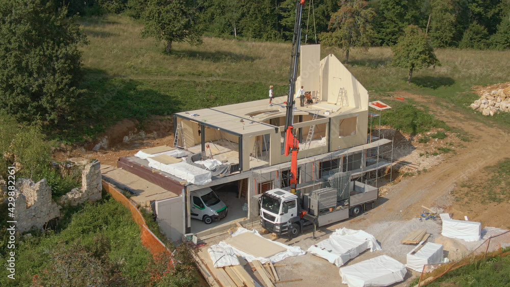 AERIAL: Boom lifts CLT wall panels during construction of modern housing project