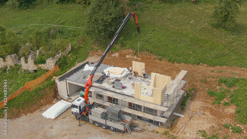 AERIAL: Truck boom operator helps contractors working on building CLT house.