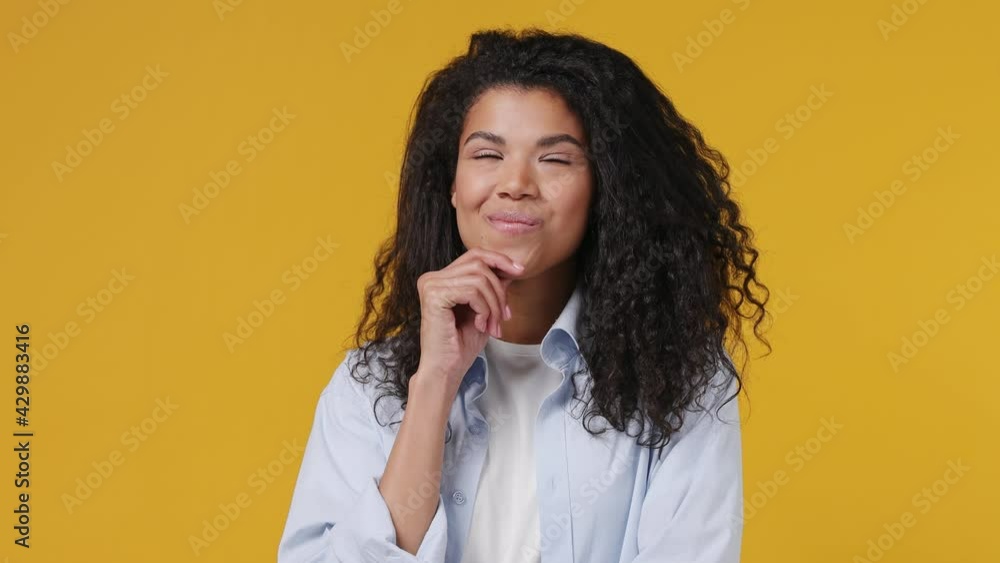 Young fun african woman curly hair 20s years old wears blue white t shirt looking around think dream put hand prop up on chin isolated on yellow color wall background studio People lifestyle concept Young fun african woman curly hair 20s years old wears blue white t shirt looking around think dream put hand prop up on chin isolated on yellow color wall background studio People lifestyle concept