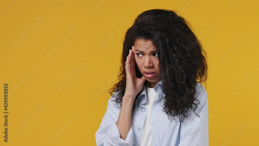 Puzzled thoughtful gloomy young african woman 20s years old wears blue white t shirt look aside put hand prop up on chin iterates over solution options isolated on yellow color wall background studio Puzzled thoughtful gloomy young african woman 20s years old wears blue white t shirt look aside put hand prop up on chin iterates over solution options isolated on yellow color wall background studio