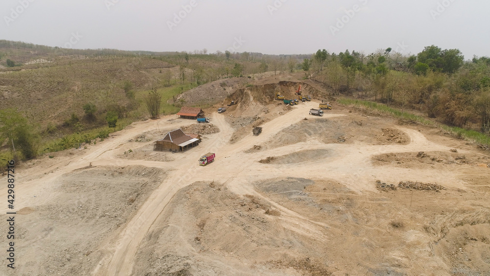 excavator at construction site cuts hill and loads truck with earth. aerial view Heavy machinery prepares the countryside for construction. Excavators are been used in large and small scale excavator at construction site cuts hill and loads truck with earth. aerial view Heavy machinery prepares the countryside for construction. Excavators are been used in large and small scale