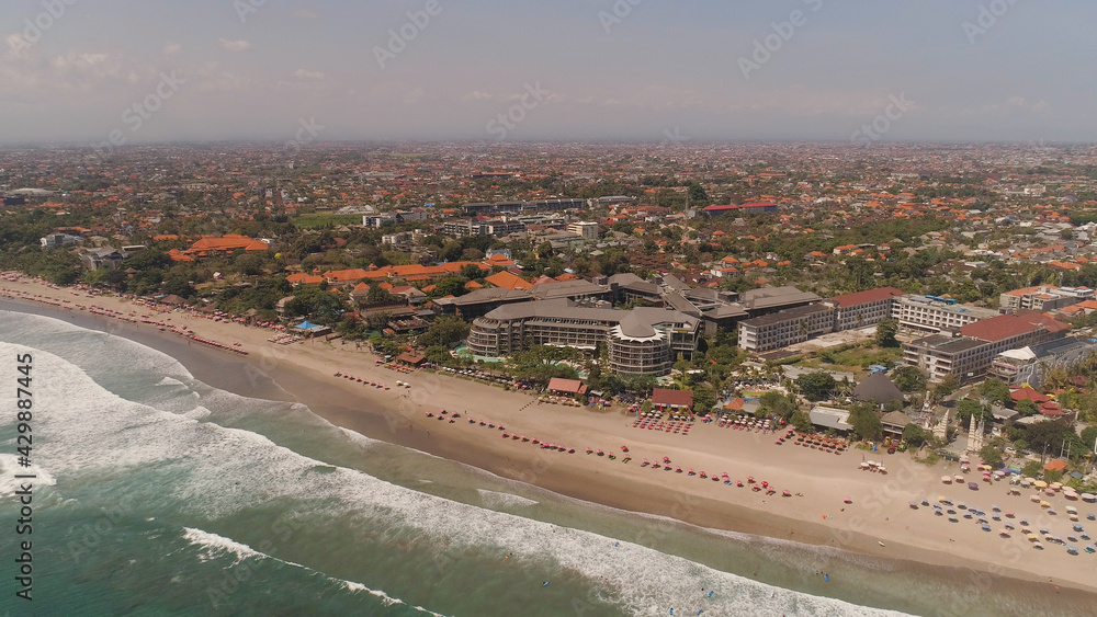 Aerial view sand beach with resting people, hotels and tourists, sun umbrellas, Bali, Kuta. surfers on water surface. Seascape, beach, ocean, sky sea Travel concept