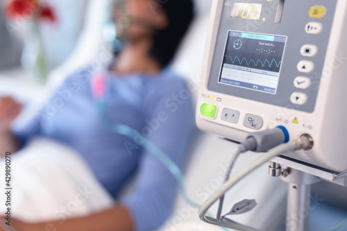 Ventilator monitor and african american female patient in hospital bed with oxygen ventilator