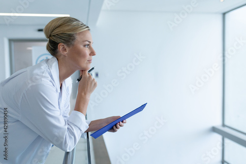 Slika na platnu Caucasian female doctor standing in hospital corridor holding medical chart docu