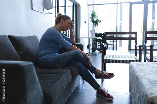 Vászonkép Caucasian female sitting on couch in hospital waiting room and worrying