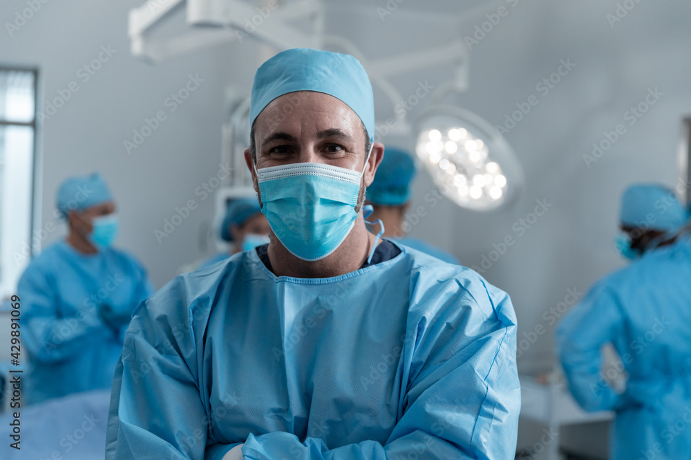 Portrait of caucasian male surgeon wearing face mask and protective clothing in operating theatre Portrait of caucasian male surgeon wearing face mask and protective clothing in operating theatre