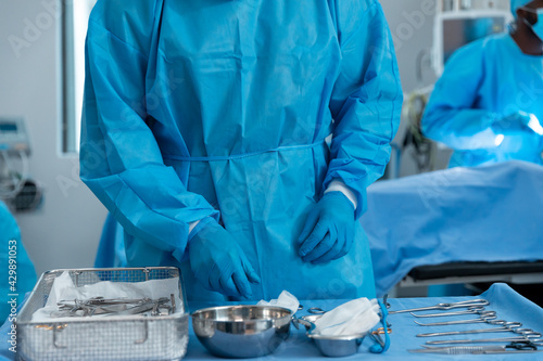 Midsection of male surgeon wearing protective clothing in operating theatre