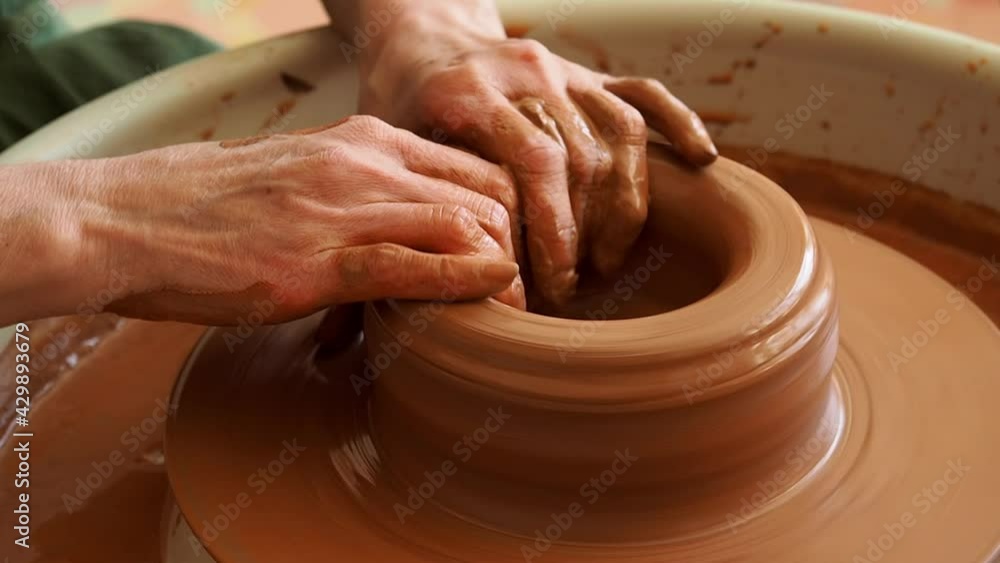 close-up of the hand of a master potter working on a potter's wheel, forming a bowl of red clay. close-up of the hand of a master potter working on a potter's wheel, forming a bowl of red clay.
