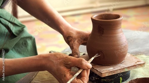 Female hands of a master potter prepares a place for a pot handle