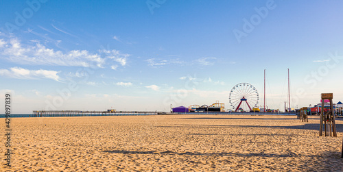 Empty beach of the popular tourist destination, Ocean City, Maryland. Image shows an afternoon view of the pier, board walk, shops, ferris wheel, lifeguard stands and the ocean at distance. photo