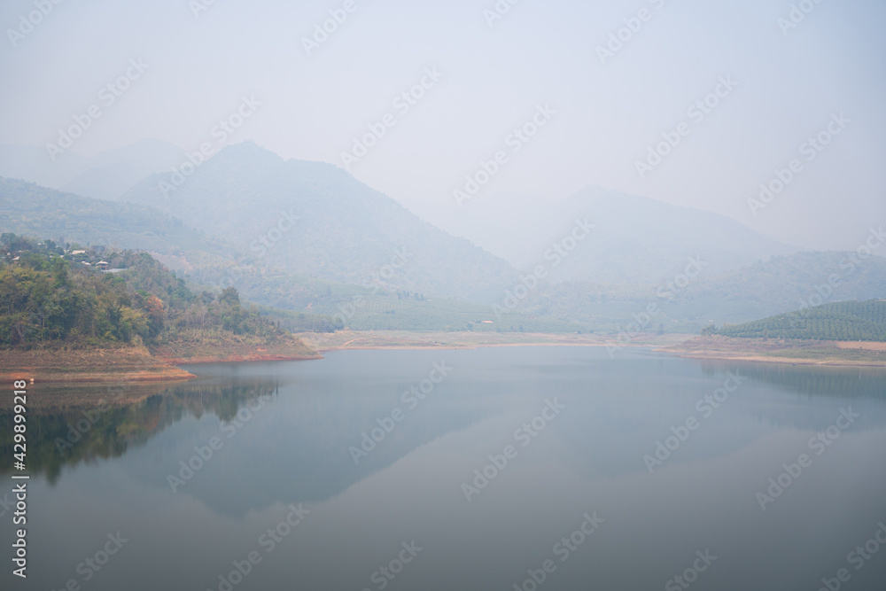 Beautiful  lake with reflection of the  mountains, smog and polluted air pollution from particle PM2.5
