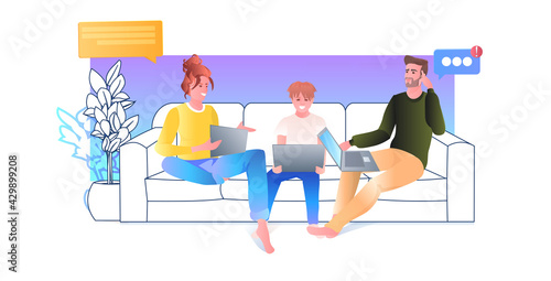 family using laptops parents wih child relaxing on sofa social media online communication concept