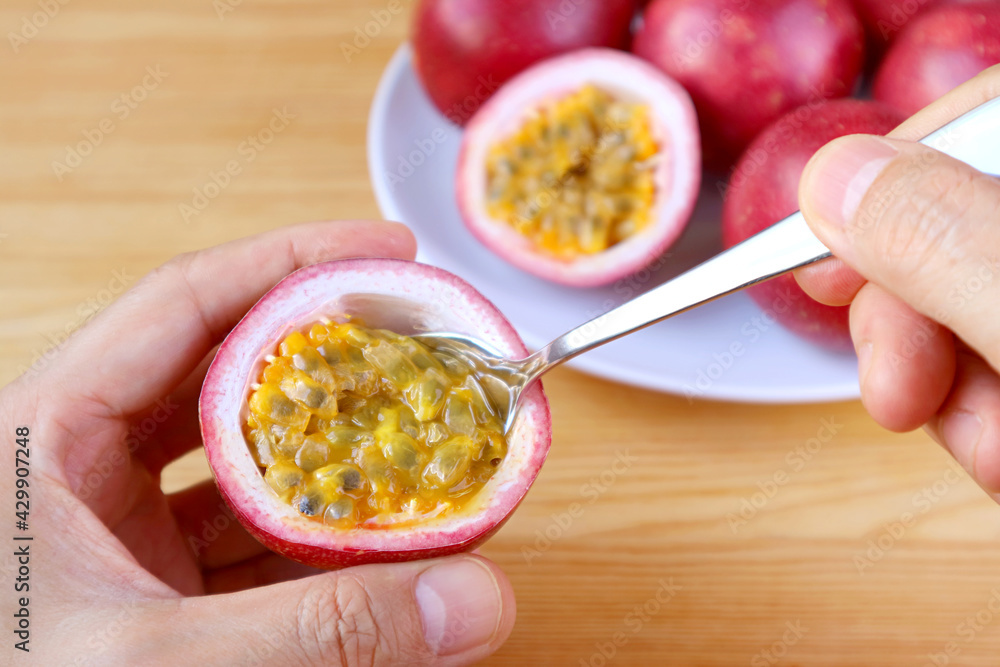 Man's Hand Scooping Fresh Ripe Passion Fruit from Its Shell with a Spoon Man's Hand Scooping Fresh Ripe Passion Fruit from Its Shell with a Spoon