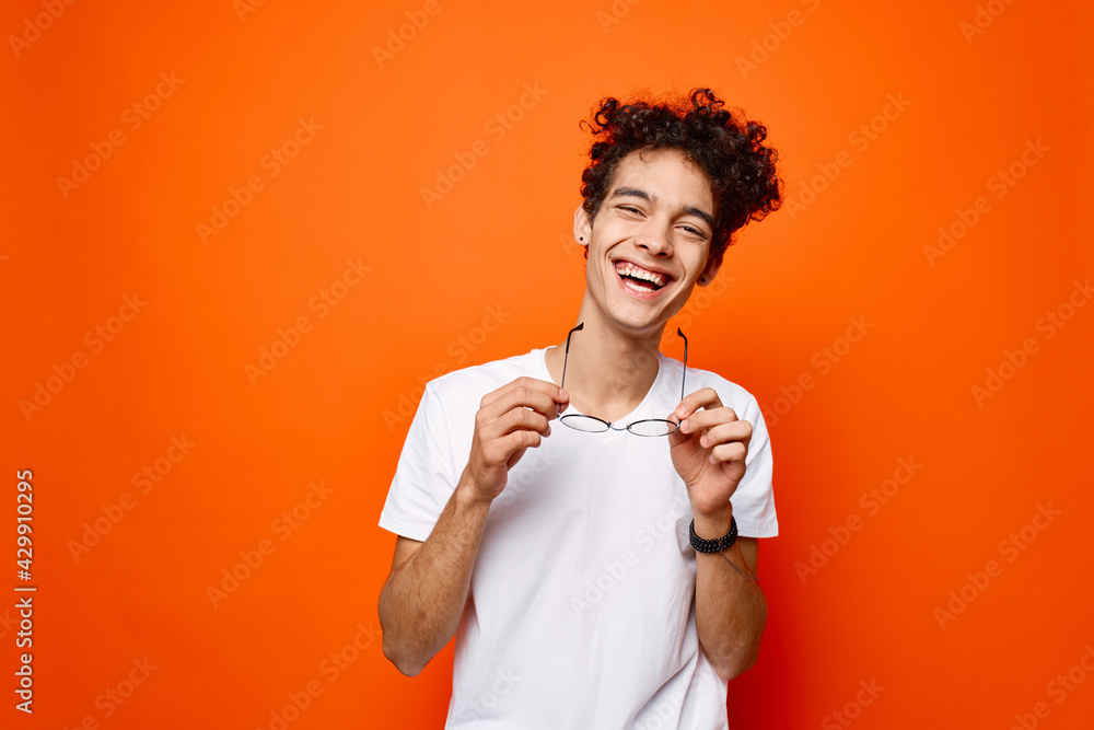 Cheerful guy curly hair glasses fashion orange background