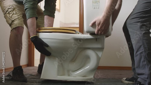 Two men carry a toilet during bathroom renovation