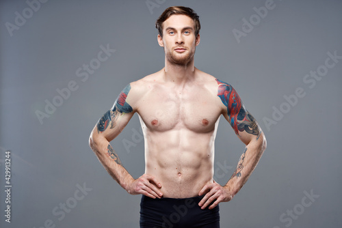 sporty man pumped up press acting out on his arms cropped view gray background
