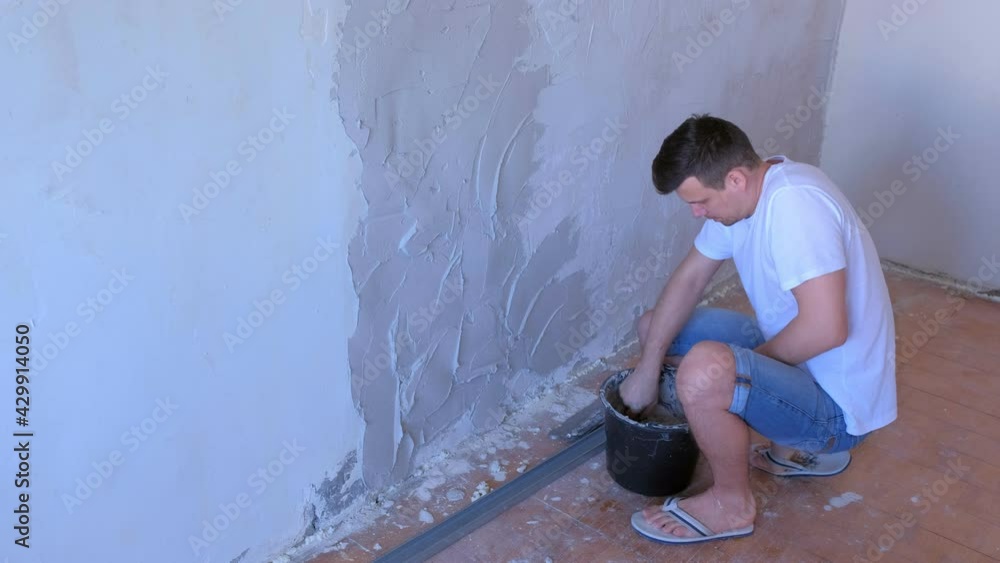 Plasterer man applying plaster on wall to aligning wall using spatula ...