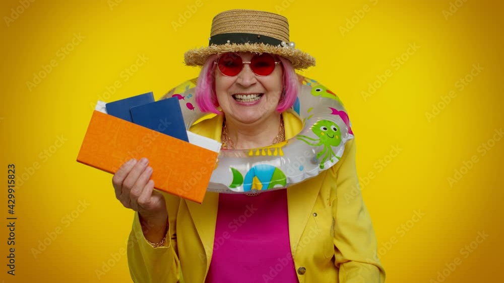 Traveler tourist senior woman holding passport tickets dreams of which country to go rest on vacation after coronavirus quarantine on studio orange background. Air flight journey. Winner celebrate Traveler tourist senior woman holding passport tickets dreams of which country to go rest on vacation after coronavirus quarantine on studio orange background. Air flight journey. Winner celebrate