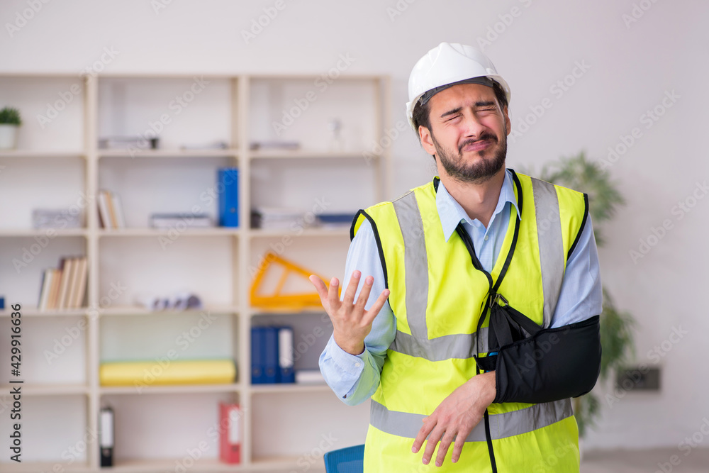 Young arm injured male architect working in the office Young arm injured male architect working in the office