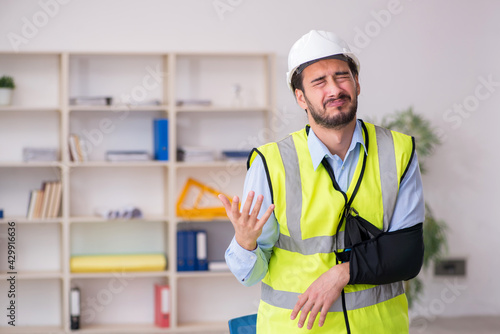 Young arm injured male architect working in the office