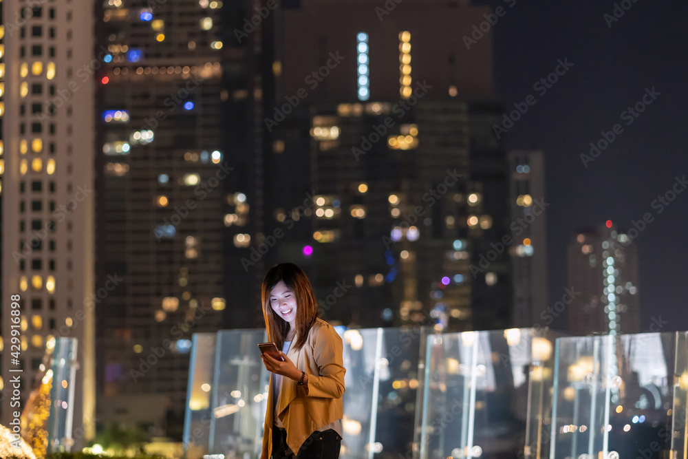 Asian businesswoman using smart mobile phone with smile action in the financial district area at bangkok river side, Thailand, technology with career concept
