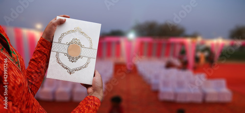 Indian wedding invitation cards with golden embroidery girl holding in hands