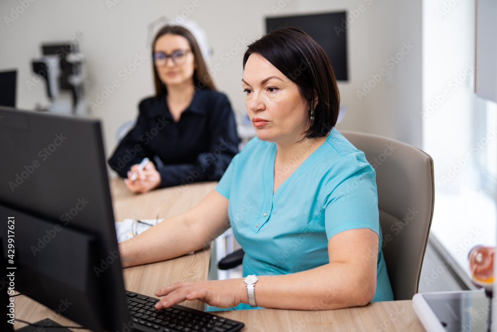 Doctor in medical office. Medical worker near computer. Medical concept. Patient waits for prescription on the blurred background. Closeup. Doctor in medical office. Medical worker near computer. Medical concept. Patient waits for prescription on the blurred background. Closeup.
