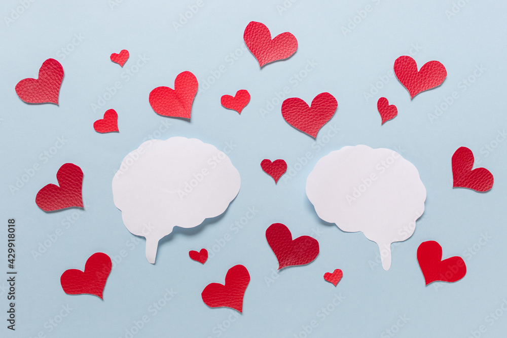 Valentine love affection paper composition with two brain silhouettes and many red hearts on blue background