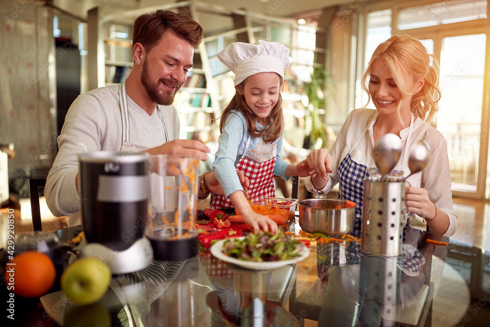 A little daughter helping her parents in meal preparation at home. Family, together, home A little daughter helping her parents in meal preparation at home. Family, together, home