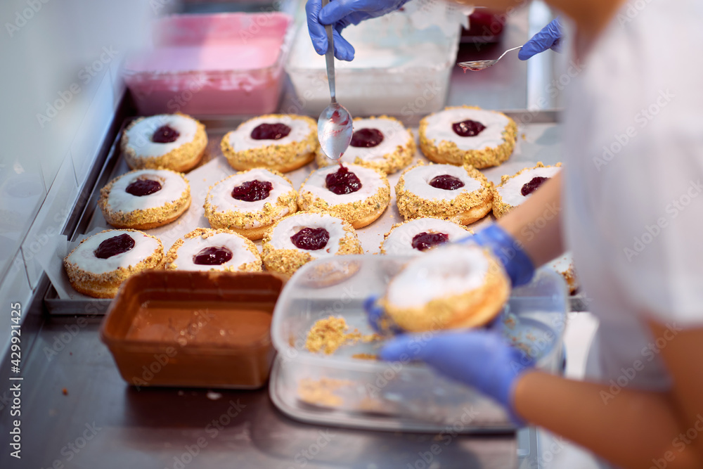 Workers fill delicious donuts with jam in a candy workshop. Pastry, dessert, sweet, making