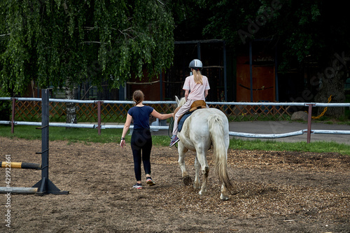 An instructor teaches a teenage girl horse riding, equestrian sports © Volodya