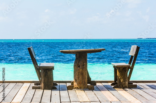 wooden table and chairs on the background of the Indian Ocean in the Maldives © dadamira