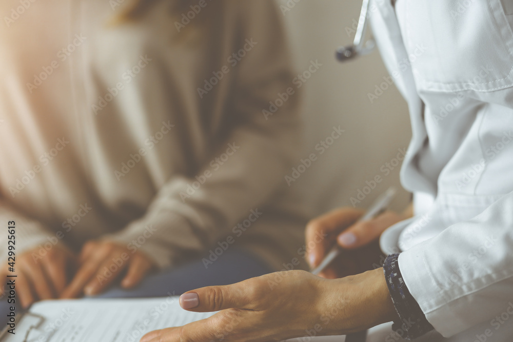 Fototapeta premium Close-up of woman-doctor and patient discussing current health examination while sitting indoors. Stay at home concept during Coronavirus pandemic and self isolation quarantine. Covid 2019
