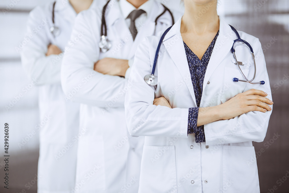 Doctors standing as a team with arms crossed in clinic. Medical help, insurance and medicine concept Doctors standing as a team with arms crossed in clinic. Medical help, insurance and medicine concept