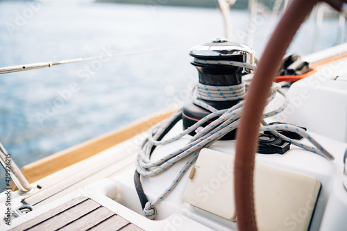 Black halyard winch with a white cable coiled around against the background of the bow of sailboat photo