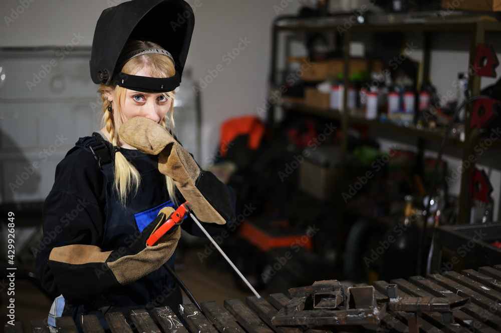 Portrait of cute caucasian girl blonde welder working in the garage