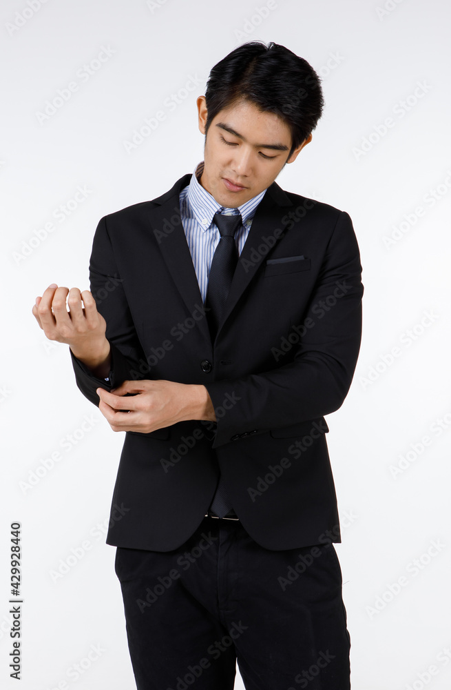 Portrait shot of Asian young healthy black short hair handsome white collar office worker in formal suit standing smiling adjusting button on sleeve in front of white background Portrait shot of Asian young healthy black short hair handsome white collar office worker in formal suit standing smiling adjusting button on sleeve in front of white background
