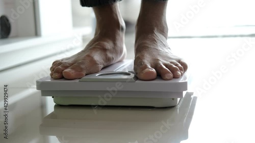 Asians foot man with body weight scales for measure weight loss.Weighing scale to healthy slimming concept.medium long shot panning dolling shift focus dolly slider for slowmotion photo