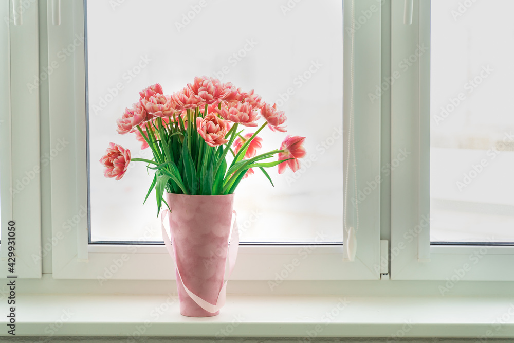 pink terry tulips in a basket stand on the windowsill pink terry tulips in a basket stand on the windowsill