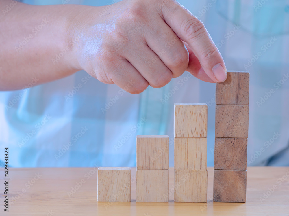 Hand arranging wood cube stacking as stair step shape on wooden table .Business concept create symbol or logo, development, growth and management concept. Hand arranging wood cube stacking as stair step shape on wooden table .Business concept create symbol or logo, development, growth and management concept.