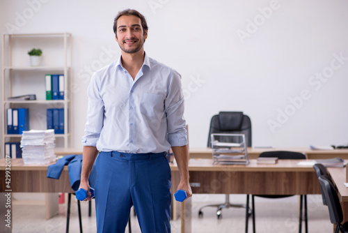 Young male employee doing sport exercises during break
