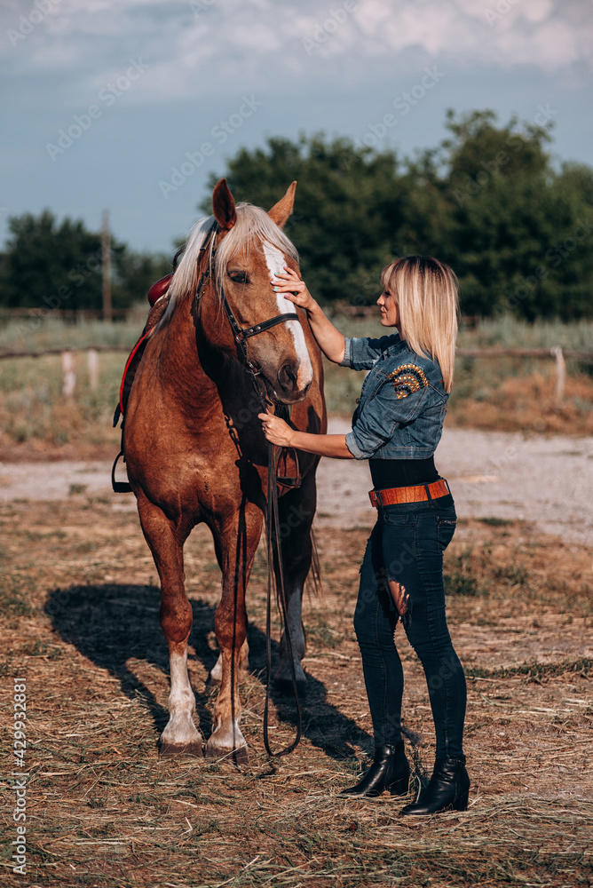 Attractive blonde woman standing near horse on rancho background Attractive blonde woman standing near horse on rancho background