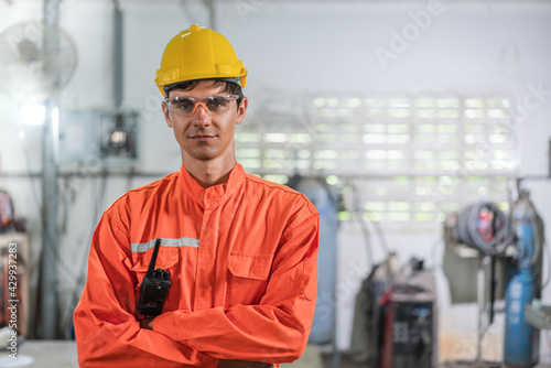 Portrait of male engineer in orange uiform cross arms standing at factory Industrial photo