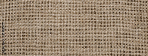 Hessian sackcloth burlap woven texture background, Cotton woven fabric close up with flecks of varying colors of beige and brown, with copy space for text decoration.