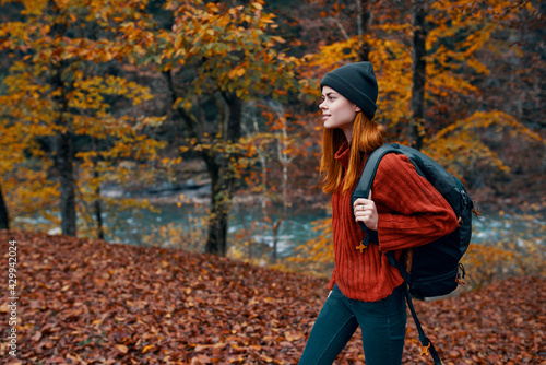 fallen leaves in the park in autumn and the river in the background woman tourist with a backpack travel