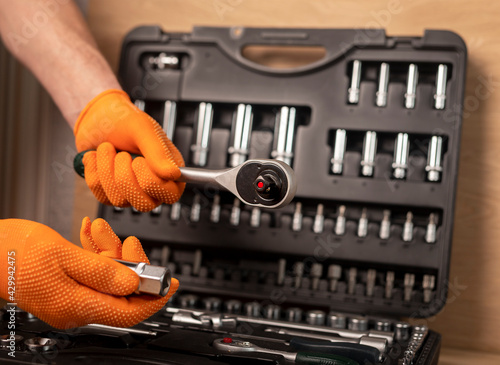 Foto Male hand in building glove with socket ratchet handle taking from repair suitcase