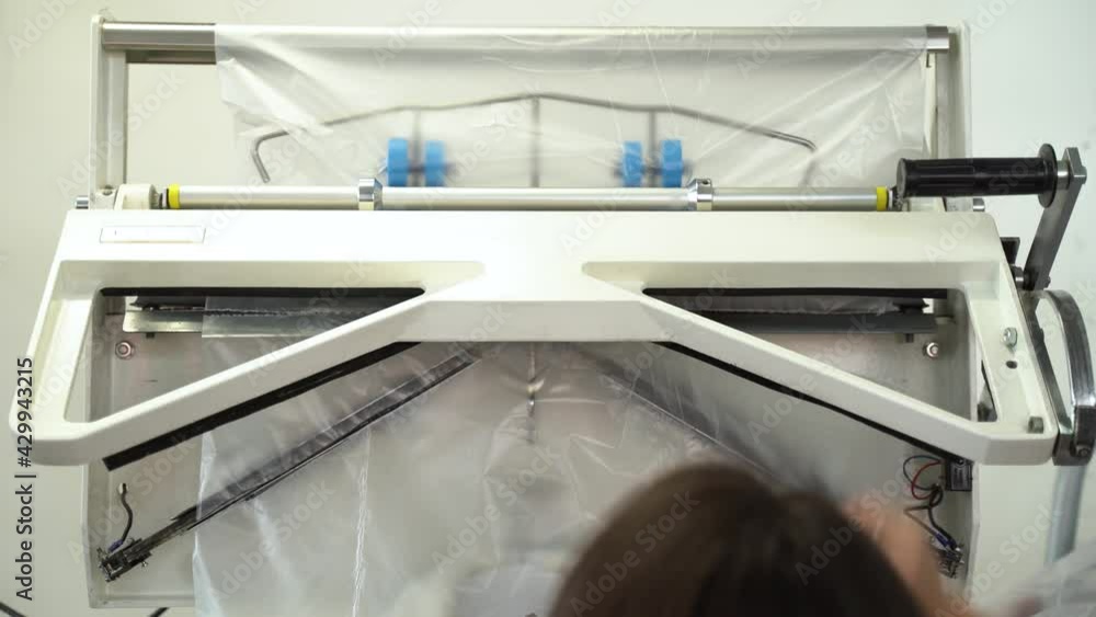 Close-up of men's suit jacket hanging during packing in polyethylene after dry-cleaning in salon. Special equipment packing clean clothes on hangers at the end of professional dry cleaning Close-up of men's suit jacket hanging during packing in polyethylene after dry-cleaning in salon. Special equipment packing clean clothes on hangers at the end of professional dry cleaning