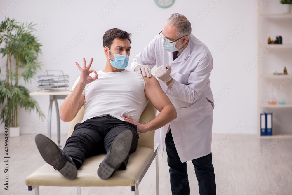 Obraz premium Young male patient visiting old male doctor in vaccination conce