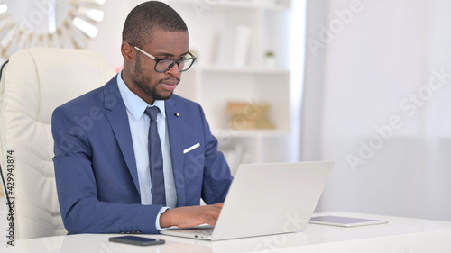 Attractive Young African Businessman Working on Laptop in Office 