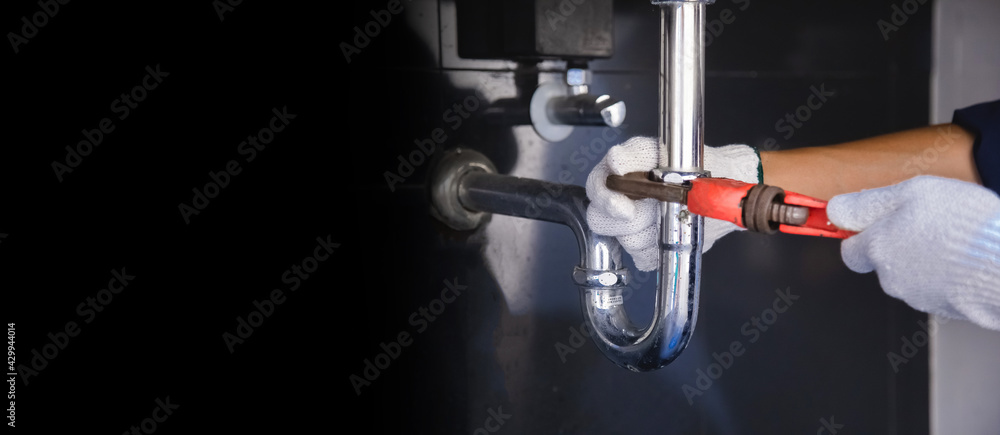 Plumber fixing white sink pipe with adjustable wrench. Plumber fixing white sink pipe with adjustable wrench.